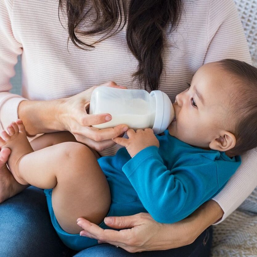 A woman is feeding her baby with a bottle.